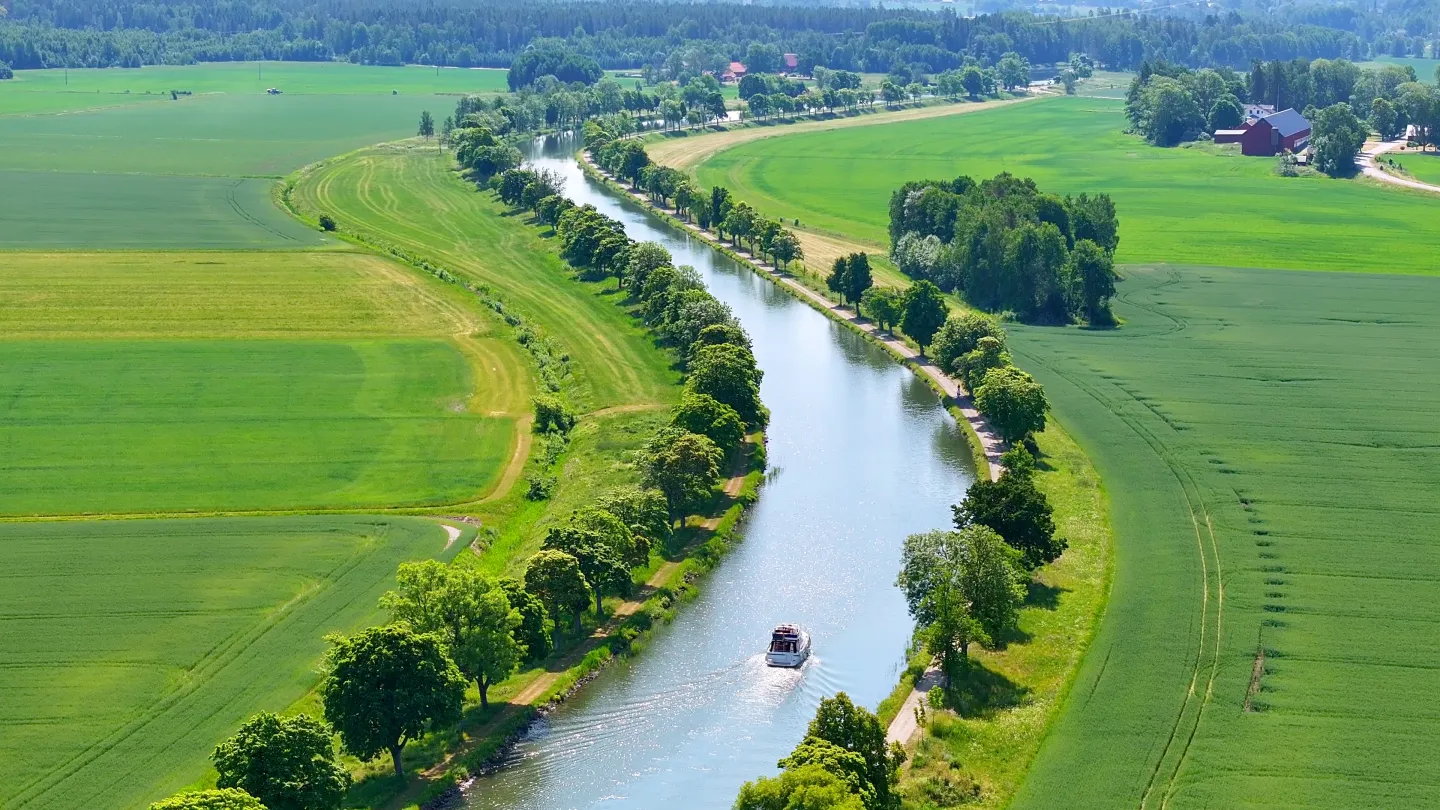 Fritidsbåt glider genom trädallén Göta kanal