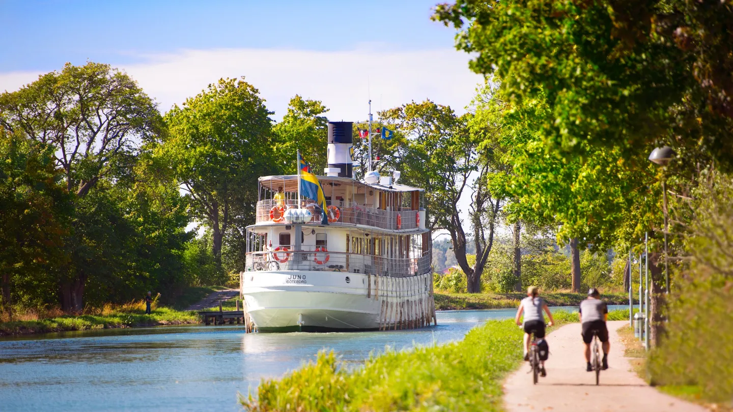 Cyklister passeras av M/S Juno på Göta kanal